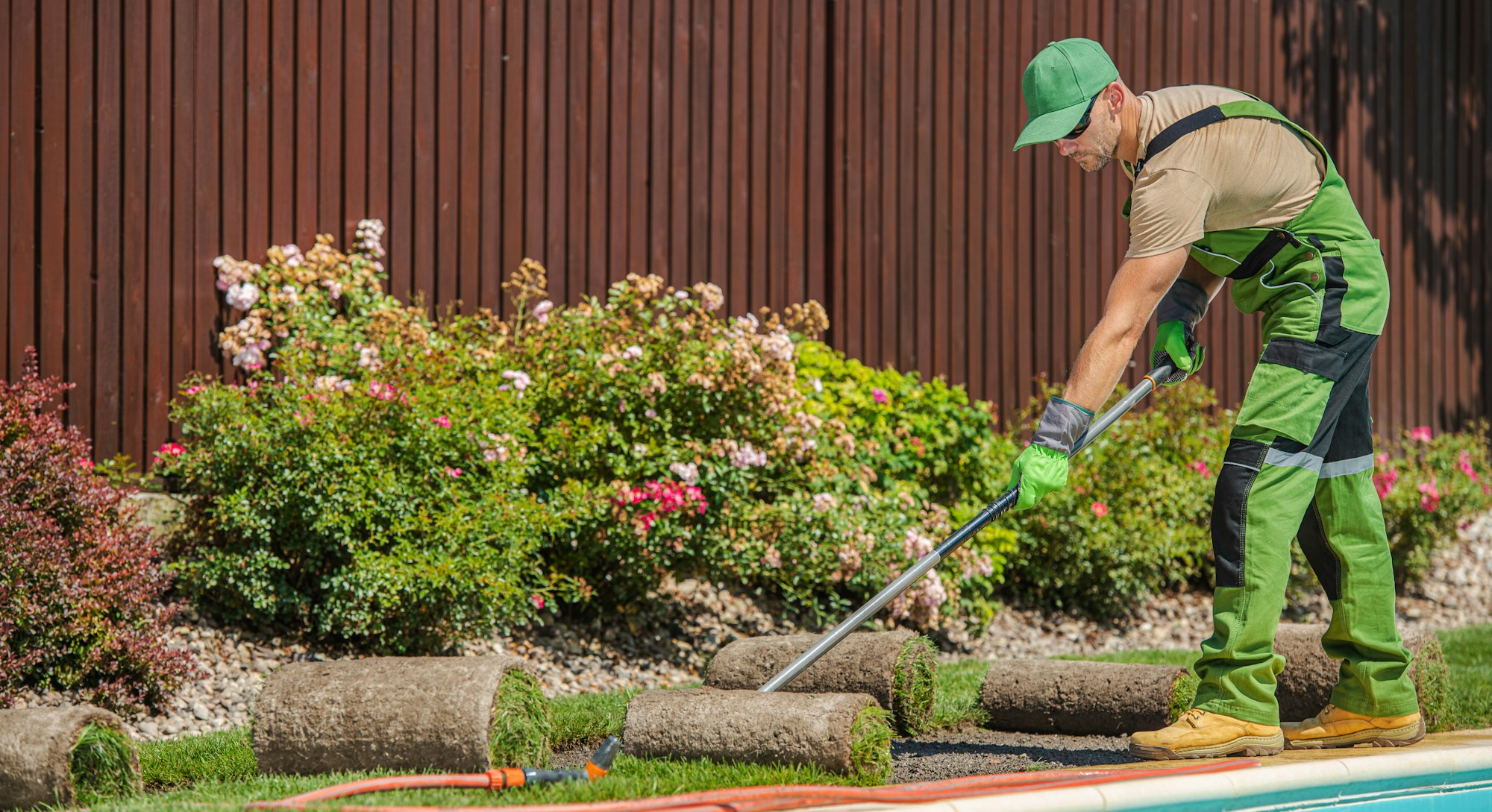 Gardener Preparing Soil For Grass Turf Installation